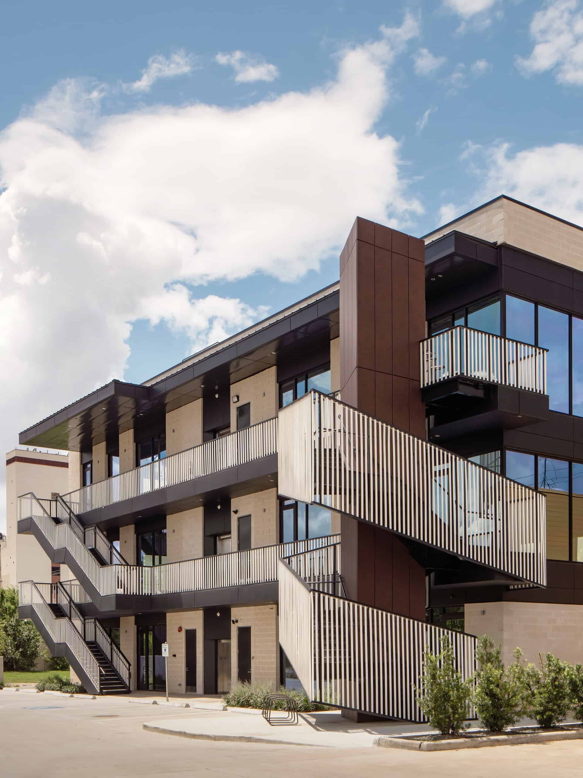 Exterior view of 3509 Harrisburg, showcasing a modern architectural design with warm metal finish, Mature Rust and a sleek blackened steel finish, Gun Metal, set against an urban backdrop.